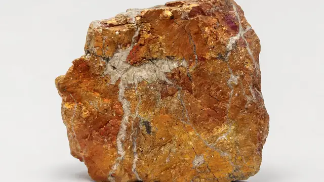 Amostra de minério de cobre de cor alaranjada sobre fundo branco