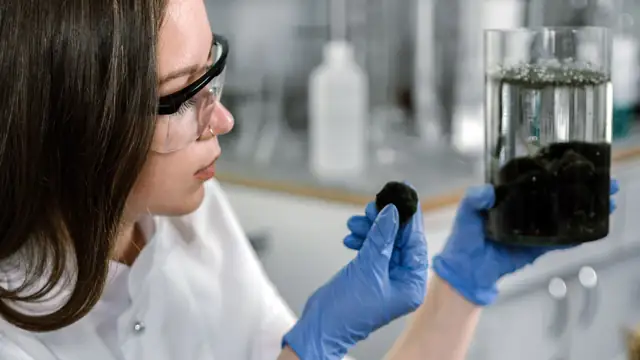 Cientista de jaleco examina uma amostra com equipamentos de laboratório