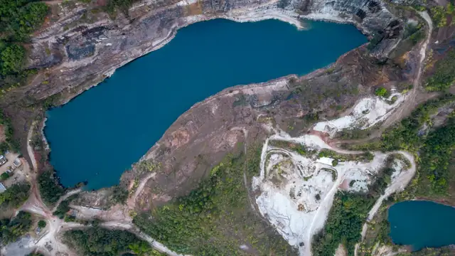 Vista aérea de uma cava de mineração com lago de água azulada cercada por vegetação