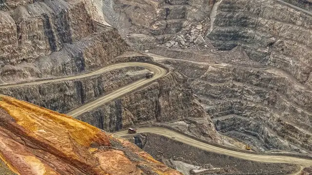 Vista aérea de estradas sinuosas em uma grande mina a céu aberto, mostrando texturas do terreno escavado