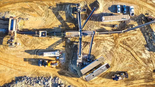 Vista aérea de área de mineração com correias transportadoras, pilhas de material e veículos