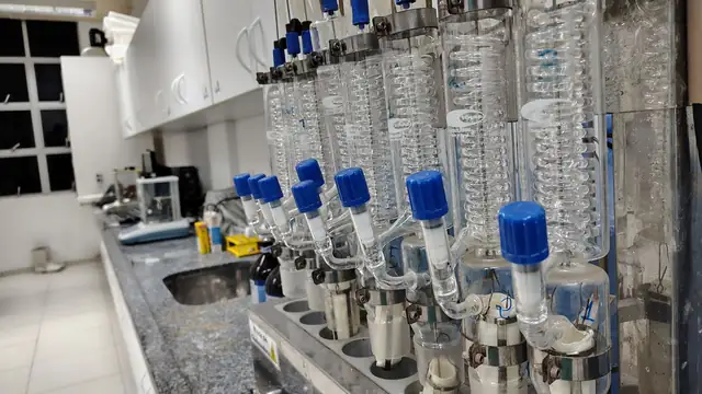 Bancada de laboratório com condensadores de vidro e outros equipamentos de análise