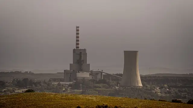 Usina térmica a carvão emitindo fumaça de suas chaminés em dia nublado
