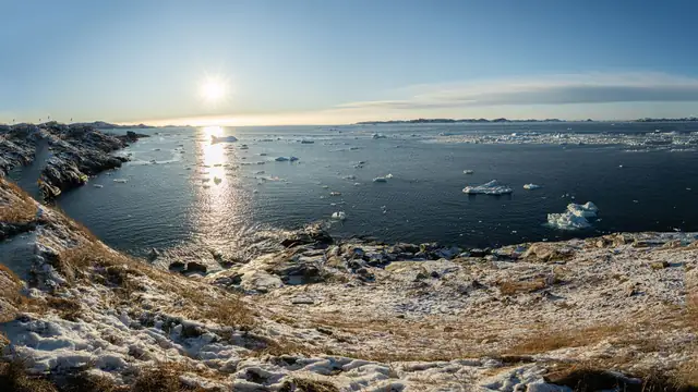 Costa nevada e águas com gelo sob sol de inverno
