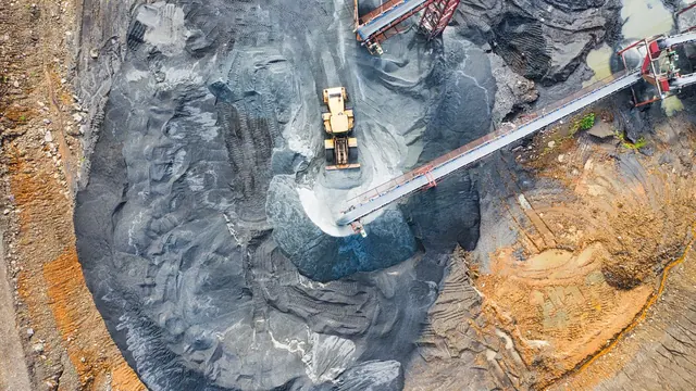 Vista aérea de mina industrial com maquinário pesado e correias transportadoras