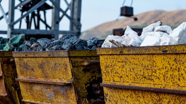Vagonetes de mineração enferrujados carregados de minério, sob estrutura metálica de uma área industrial