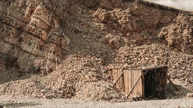 Entrada de madeira de uma mina antiga, entre encostas de rocha e cascalho