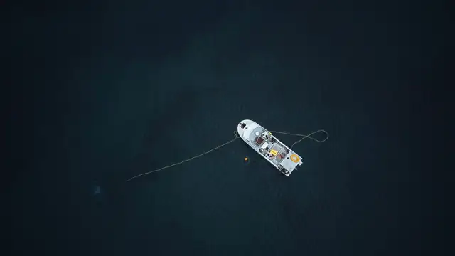 Vista aérea de uma embarcação isolada em um oceano escuro