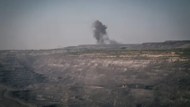 Vista aérea de pedreira com fumaça e atividade industrial de mineração