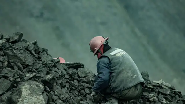 Trabalhador de capacete em uma pedreira, entre blocos de rocha