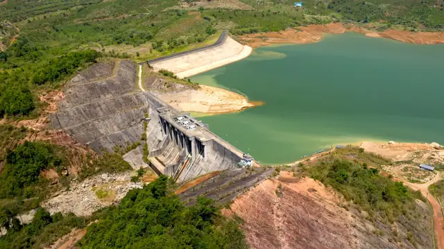 Vista aérea de uma barragem cercada por vegetação densa e por um reservatório de águas calmas