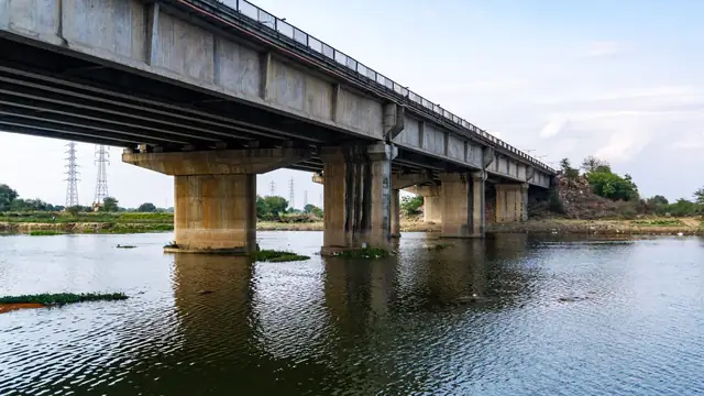 Ponte de concreto sobre um rio calmo sob céu aberto