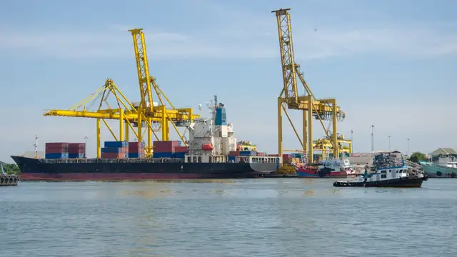 Navio de carga atracado em porto industrial, com guindastes e contêineres ao fundo