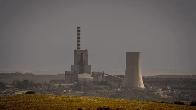 Vista distante de usina termelétrica com torres de resfriamento em uma paisagem aberta