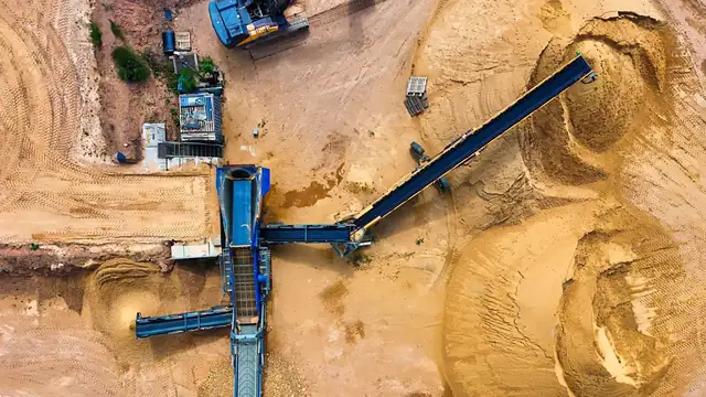 Vista aérea de maquinário e pilhas de material em área de extração a céu aberto